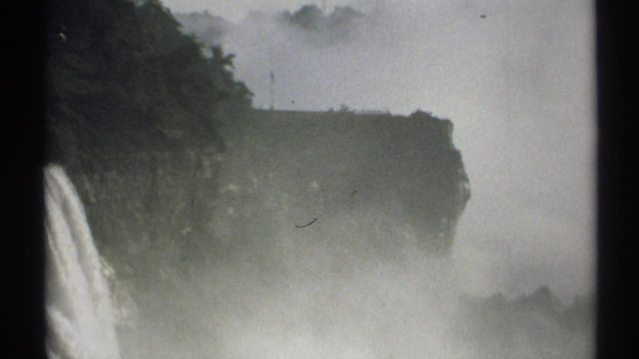 Waterfall and cliff edge partly obscured by mist.