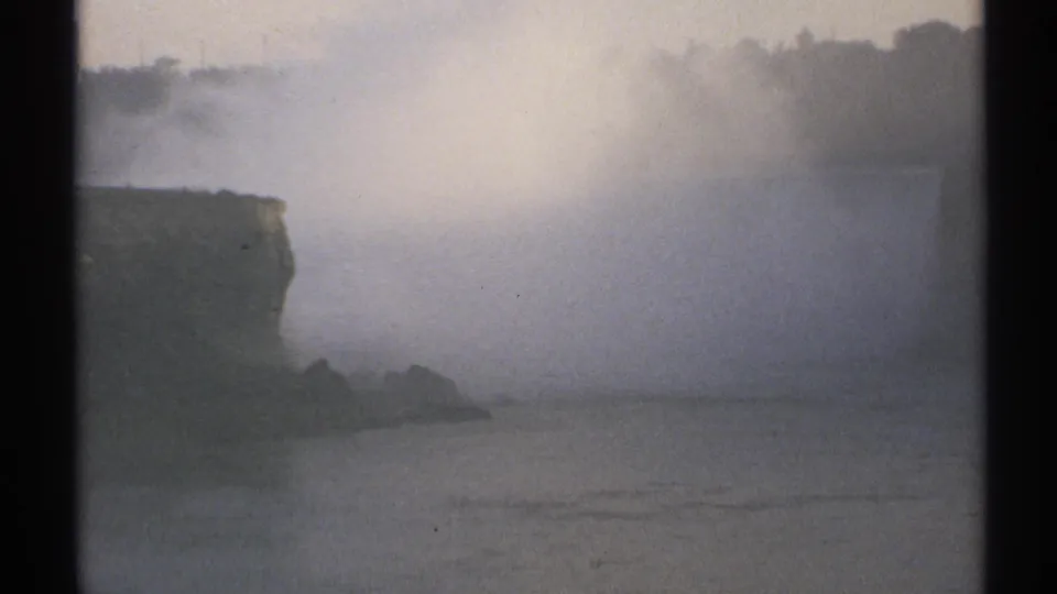 1971 New York 8mm frame showing dense spray across a broad river view with a cliff on the left.