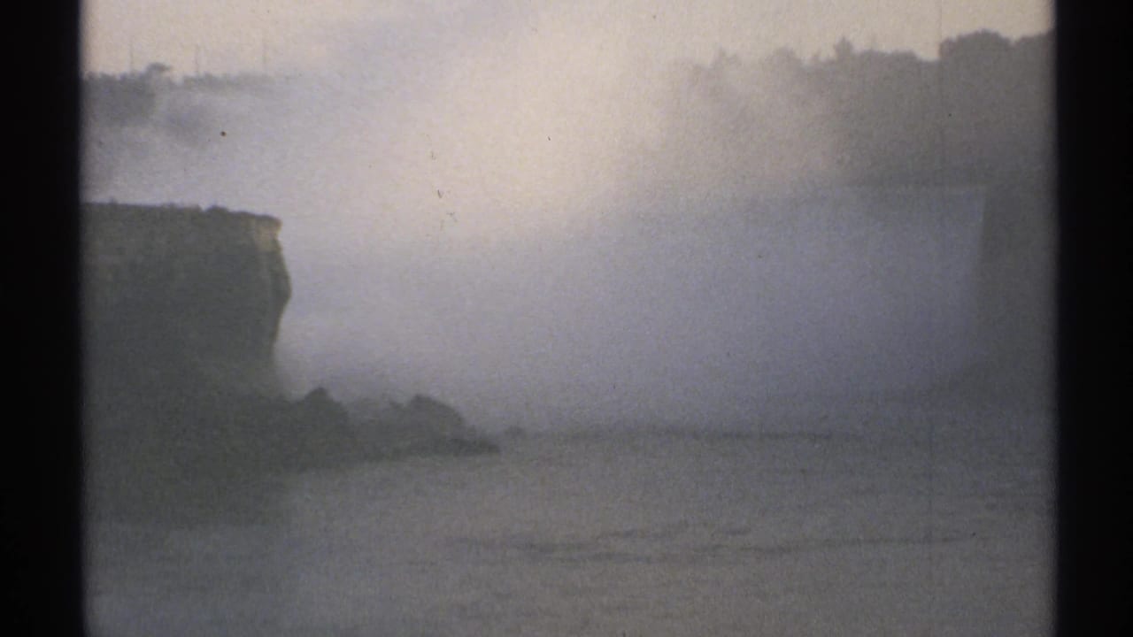 Misty view of Niagara Falls with cliffs, water, and dark film borders.