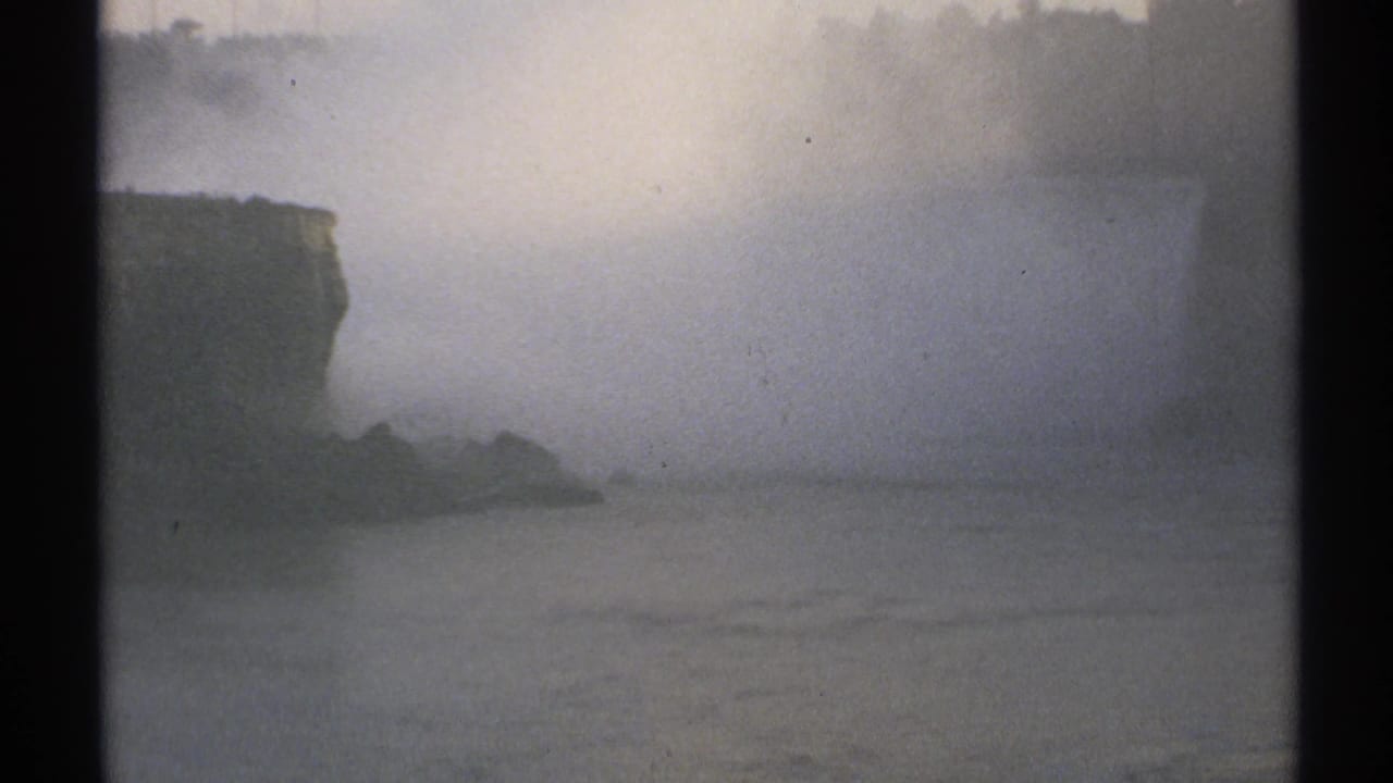 Foggy waterfall scene with rocky edge, water, treeline, and 8mm frame border.