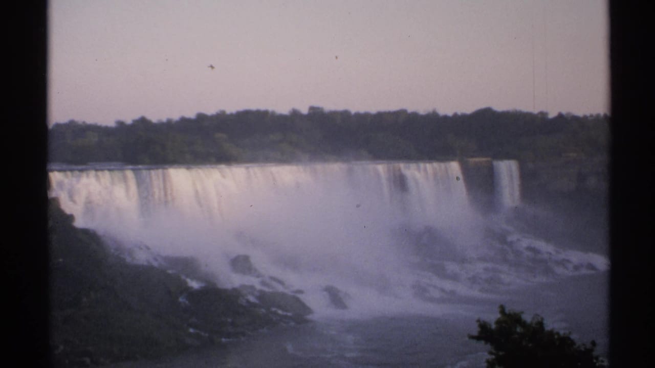 Waterfalls spill over a long cliff with dense spray across the gorge.