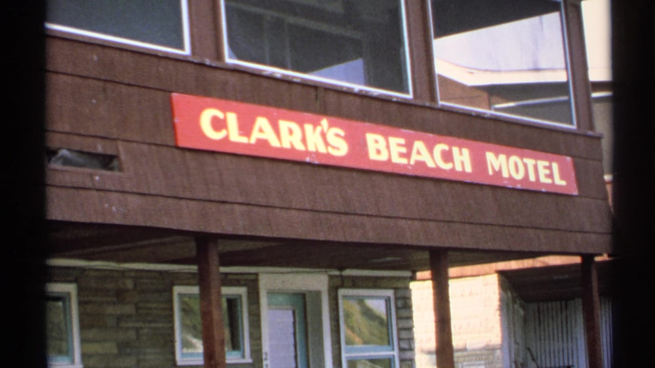 Red Clark's Beach Motel sign above a wood and stone motel exterior.