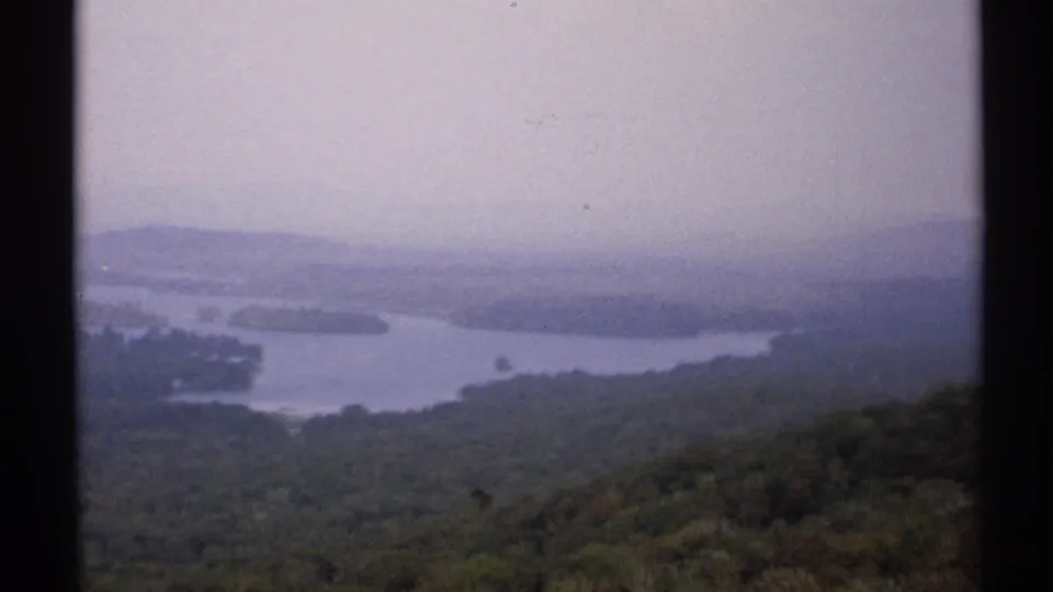 Soft 8mm view of a New York mountain overlook with a distant lake, layered hills, and muted forest color.