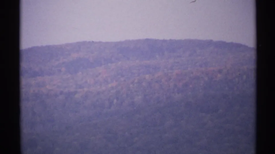 1971 New York 8mm frame showing a distant hazy mountain ridge with muted autumn colors and dark film borders.