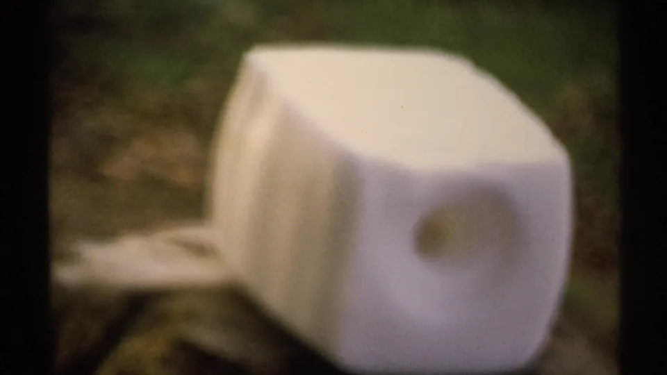 Close 1971 New York 8mm view of an unidentified white box-like object discarded on outdoor ground.