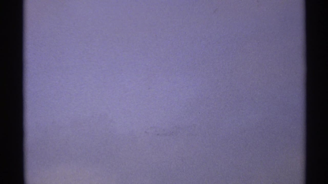 Mostly blank blue-gray overexposed frame with film grain and dark side borders.