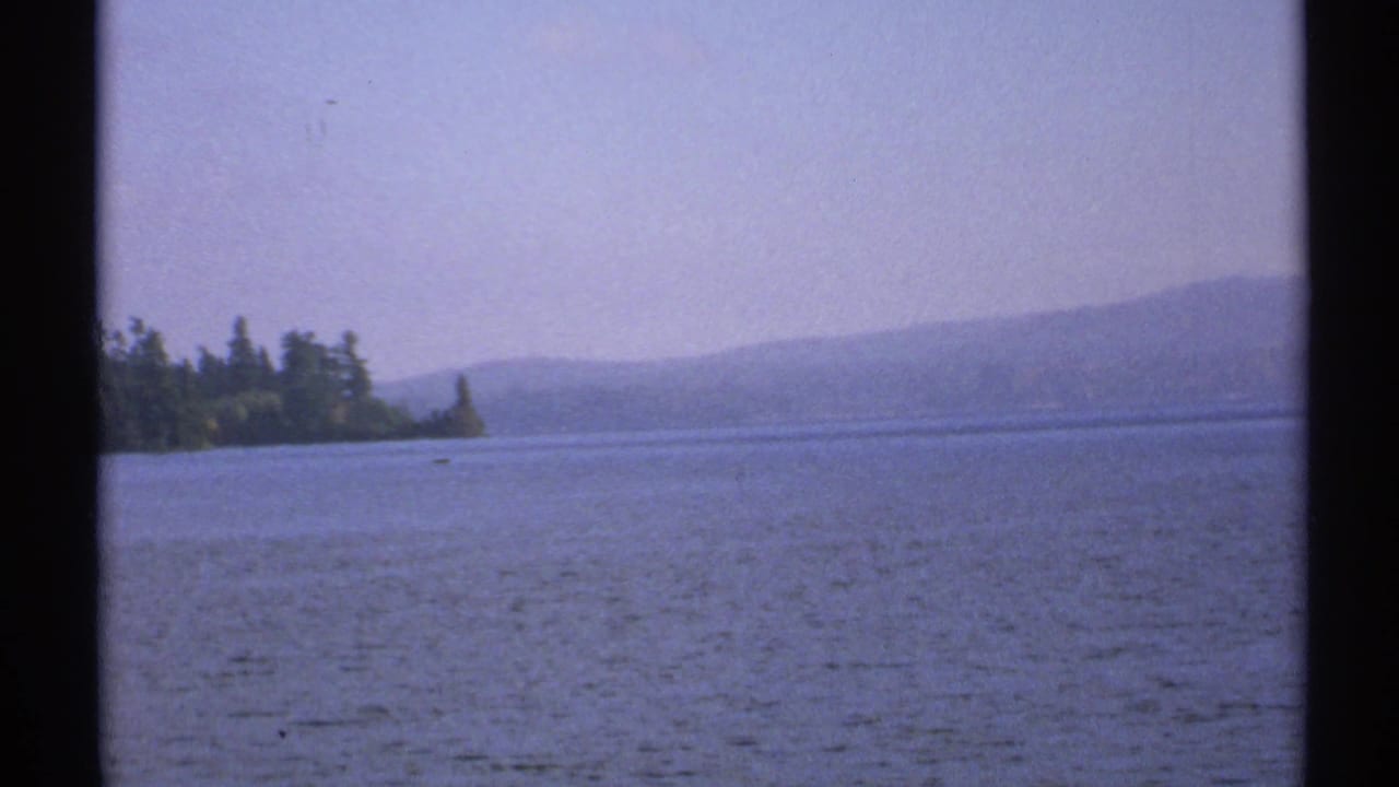 Raquette Lake landscape in New York, with calm water, tree-lined shore, and hazy hills in a soft 8mm frame.