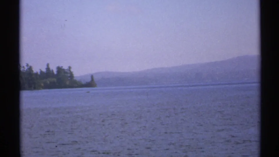 Raquette Lake landscape in New York, with calm water, tree-lined shore, and hazy hills in a soft 8mm frame.