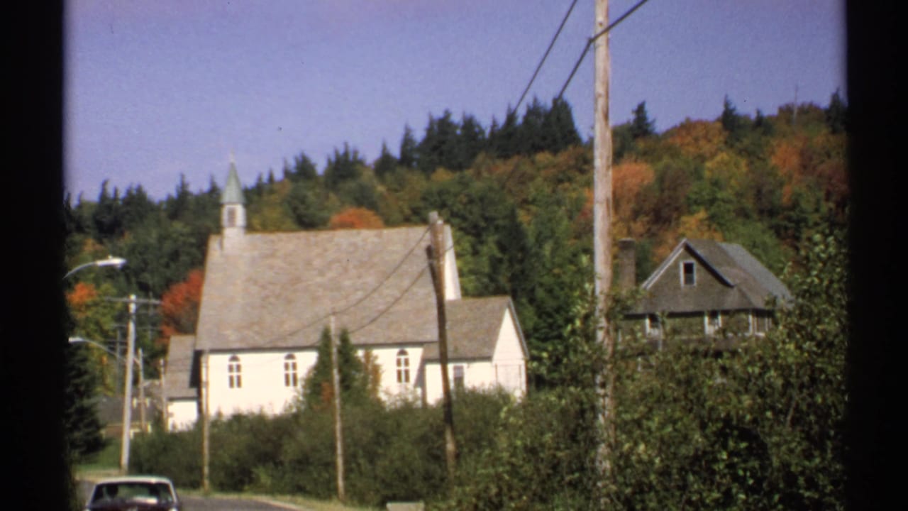 1971 New York 8mm street frame showing a white church, nearby house, utility poles, and mixed autumn trees.