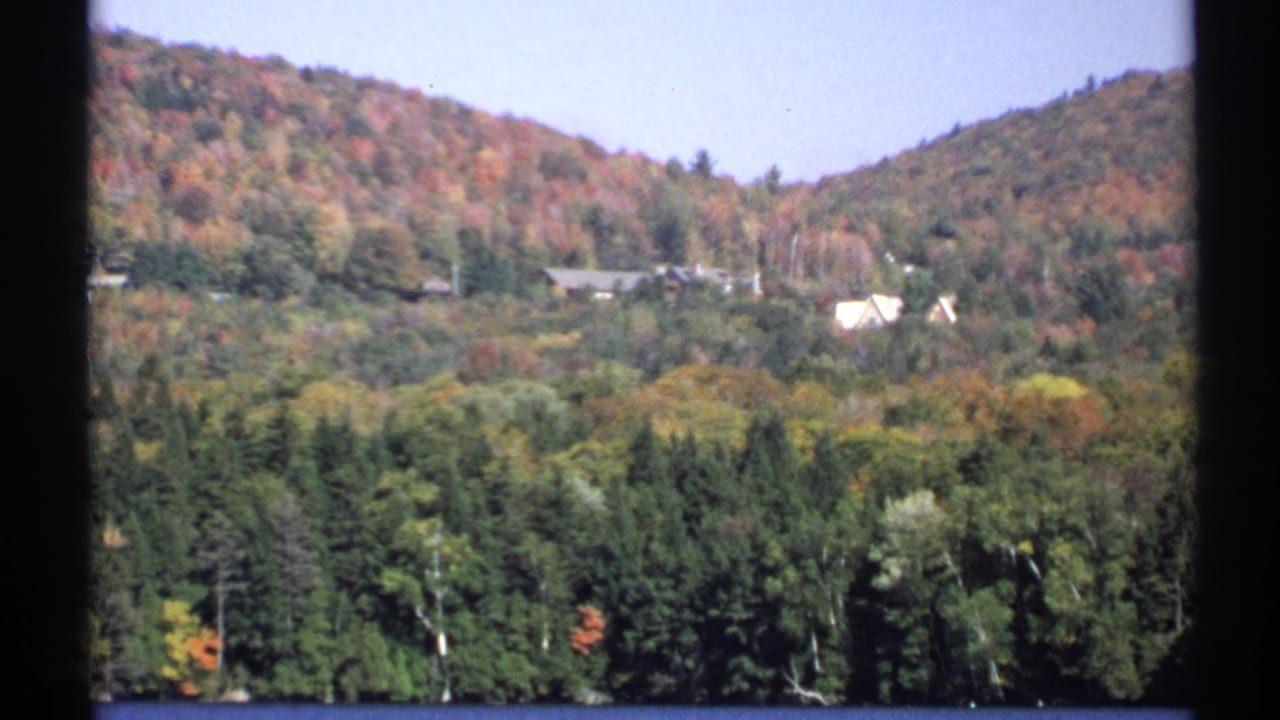 Autumn hillside with scattered rural homes and dense trees below.