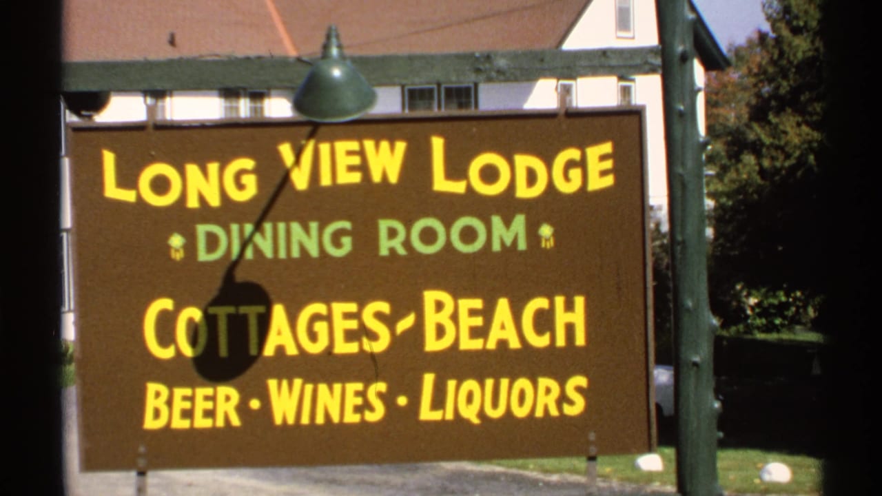 1971 New York 8mm frame showing a Long View Lodge roadside sign with dining room, cottages, beach, beer, wines, and liquors text.