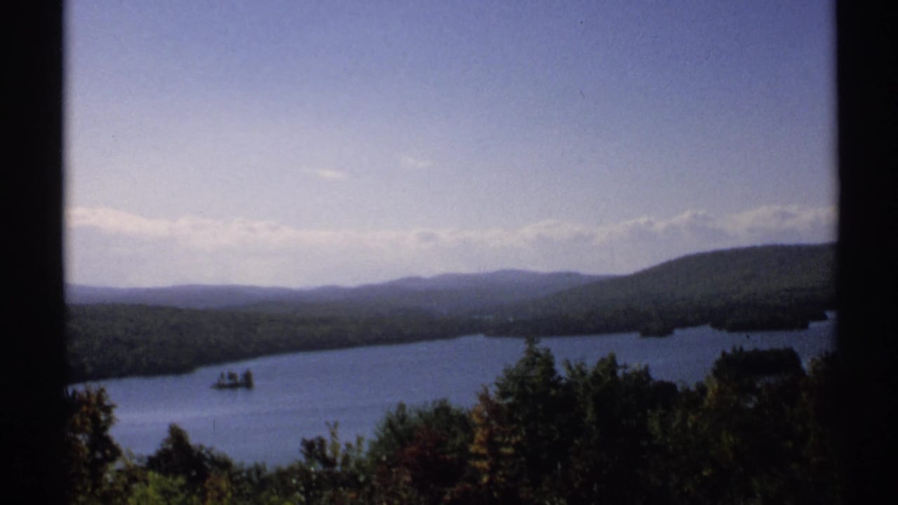 Lake and forested mountains seen through a dark window-like frame.