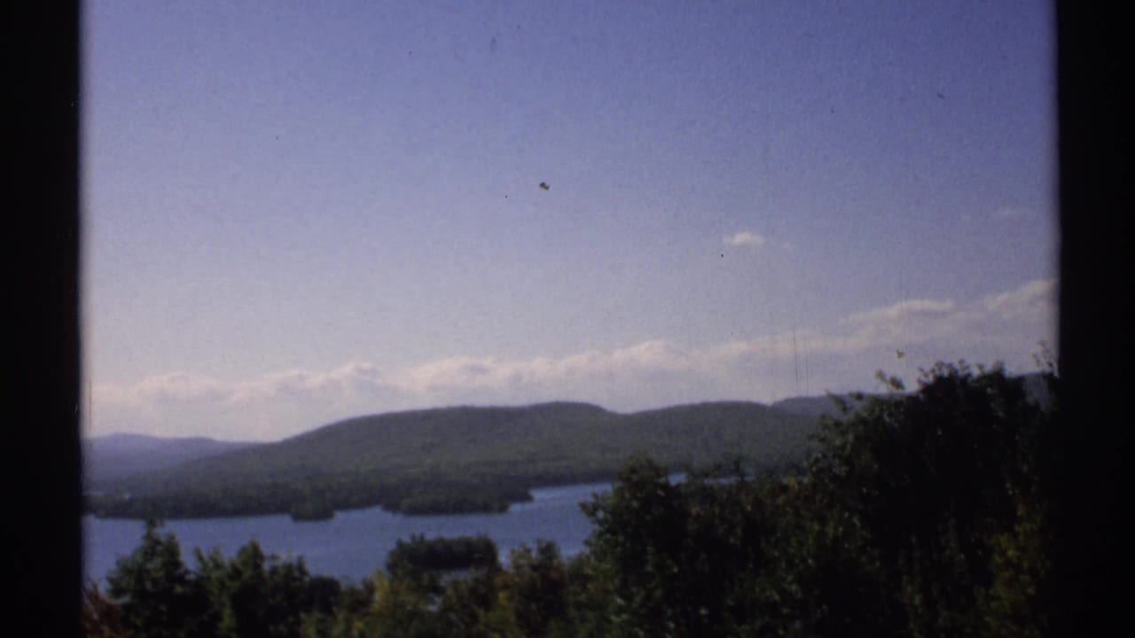 1971 New York scenic lake footage shows wooded hills, small islands, and a pale sky viewed past a dark vertical divider.