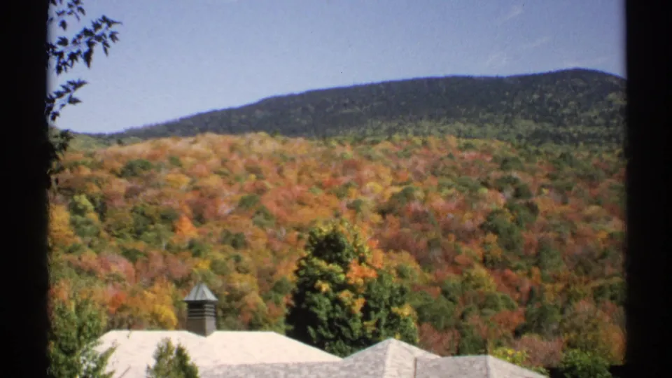 1971 New York 8mm frame showing a wooded hillside and light-colored station roofs from a visitor viewpoint.