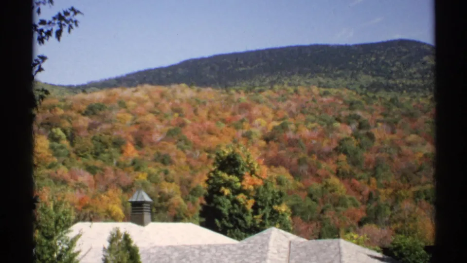 1971 New York 8mm view of wooded hills and station rooftops, framed by dark film or window edges.