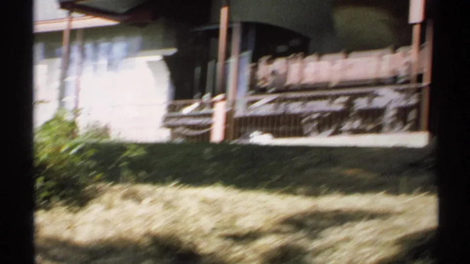 Soft, motion-blurred 1971 New York home-movie frame of the historic rail car exhibit behind a railing in bright daylight.