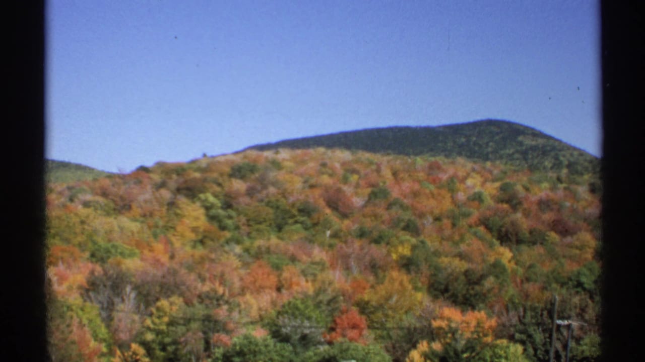 1971 New York 8mm landscape frame of forested hills in fall color beneath a clear blue sky.
