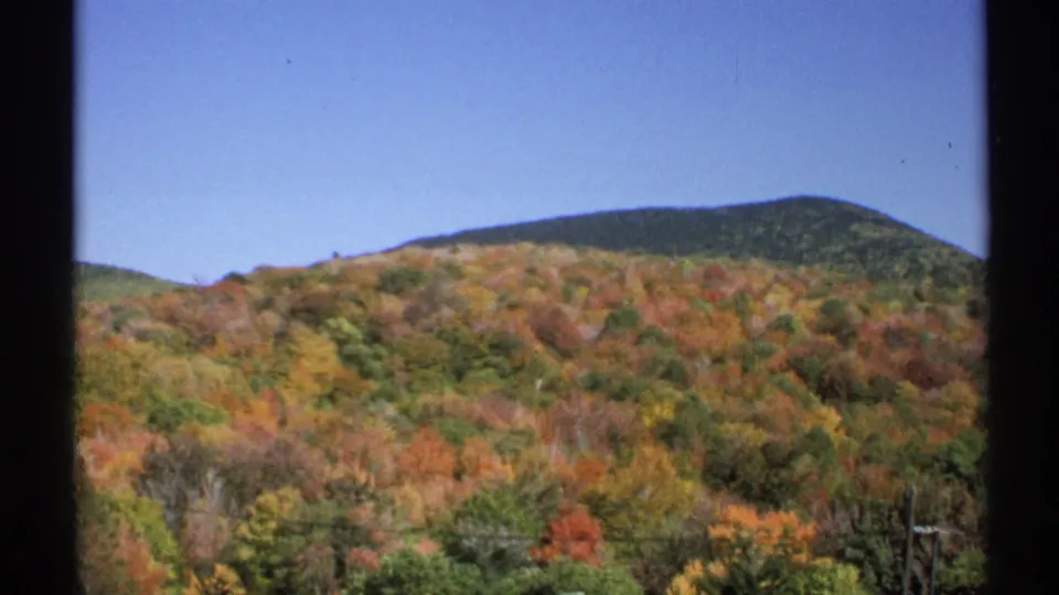 1971 New York 8mm landscape frame of forested hills in fall color beneath a clear blue sky.