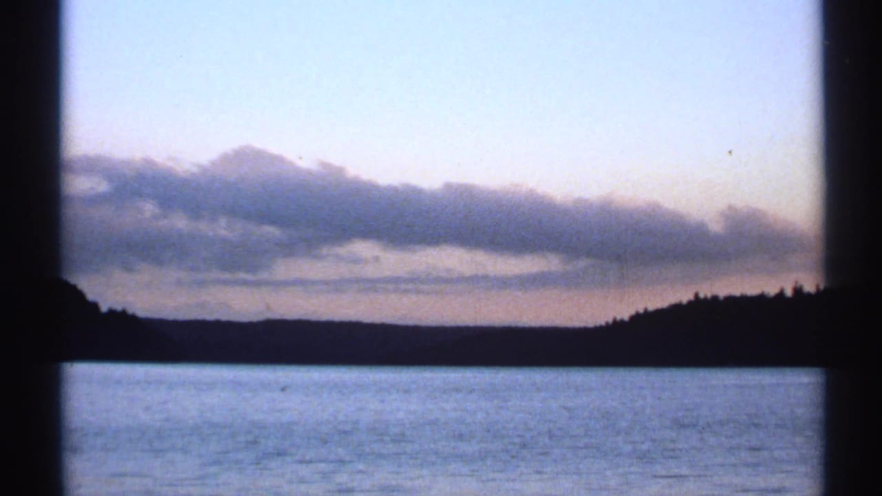 1971 New York river landscape at dusk, with a silhouetted wooded shore beneath layered clouds.