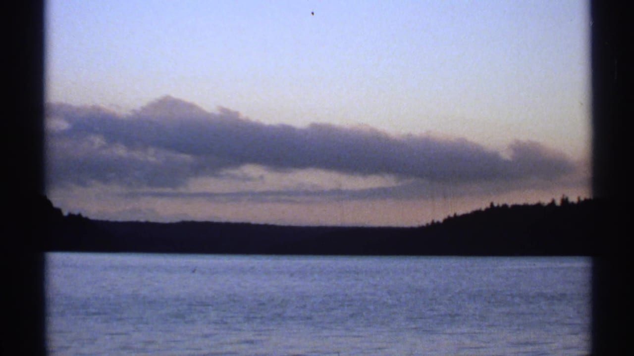 New York 8mm frame from 1971 showing a dusk river view with a tiny distant sailboat near the horizon.