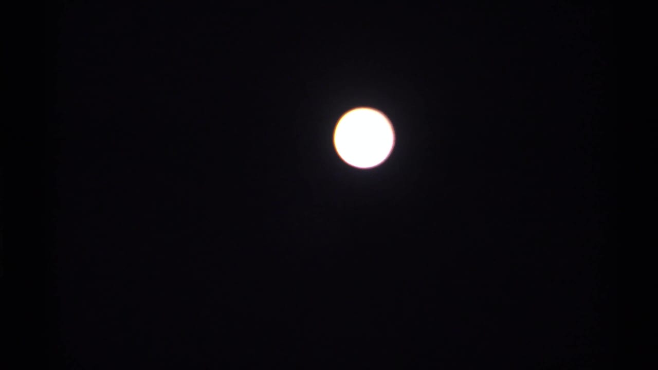 Bright white full moon against a dark night sky.