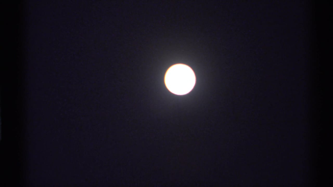 A bright moon holds in the dark sky, with the 8mm scan showing soft glow, grain, and slight exposure bloom.