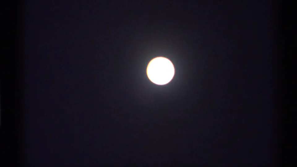 A bright moon holds in the dark sky, with the 8mm scan showing soft glow, grain, and slight exposure bloom.