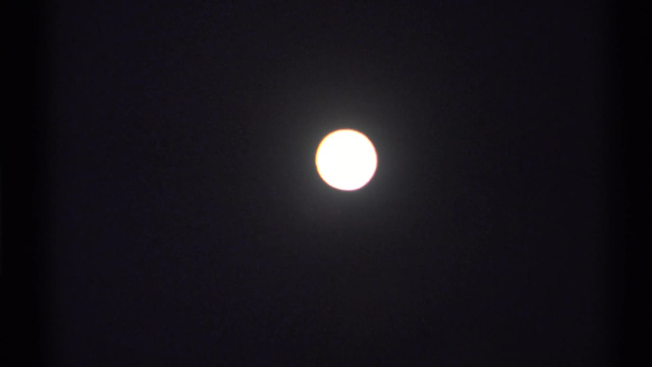 Bright circular moon against a nearly black night sky.