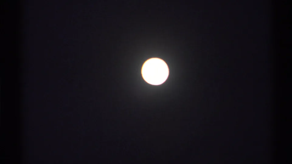 Bright overexposed moon in a dark night sky from 1971 New York home-movie footage.