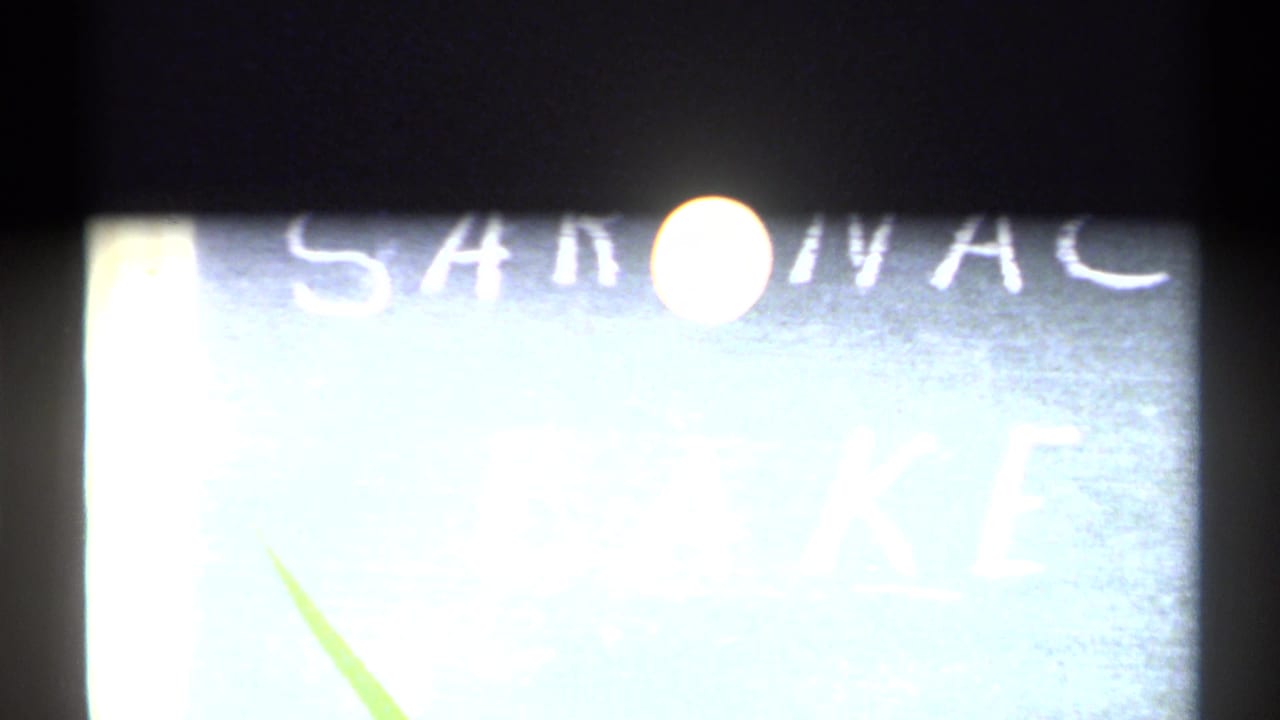 Bright moon over a partial hand-painted Saranac Lake sign in 1971 New York home-movie footage.