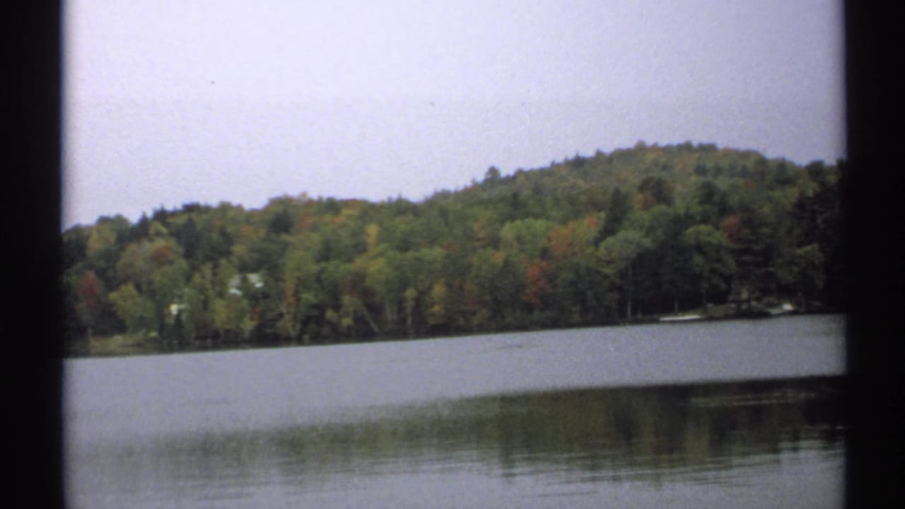 Wide lake view with wooded hillside and still water.