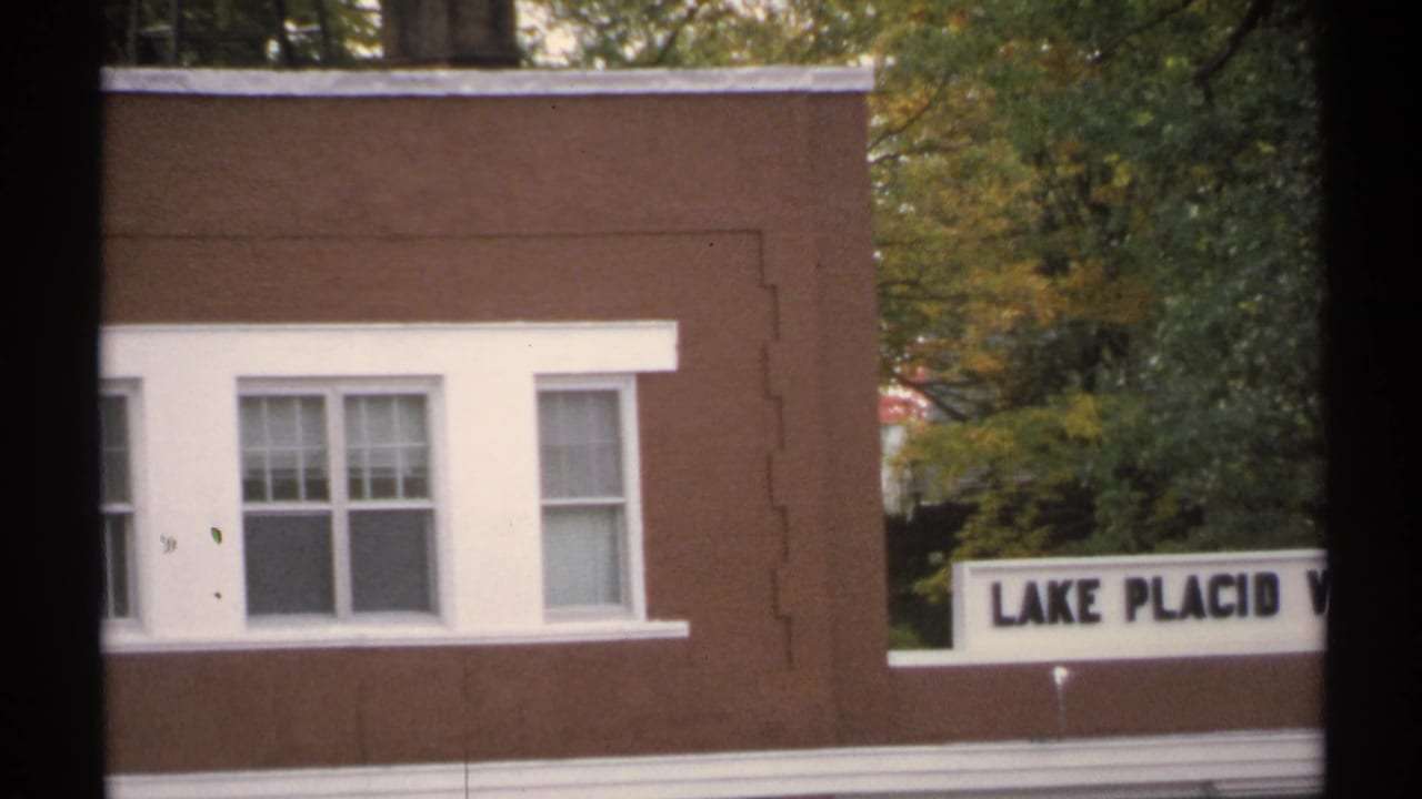 Brown building with white-trimmed windows and a partial Lake Placid sign.
