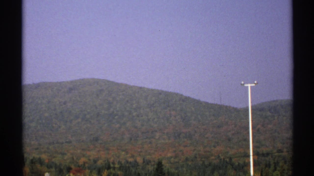 1971 New York 8mm view across autumn-colored wooded hills, with a utility pole near the right side and dark trees below.