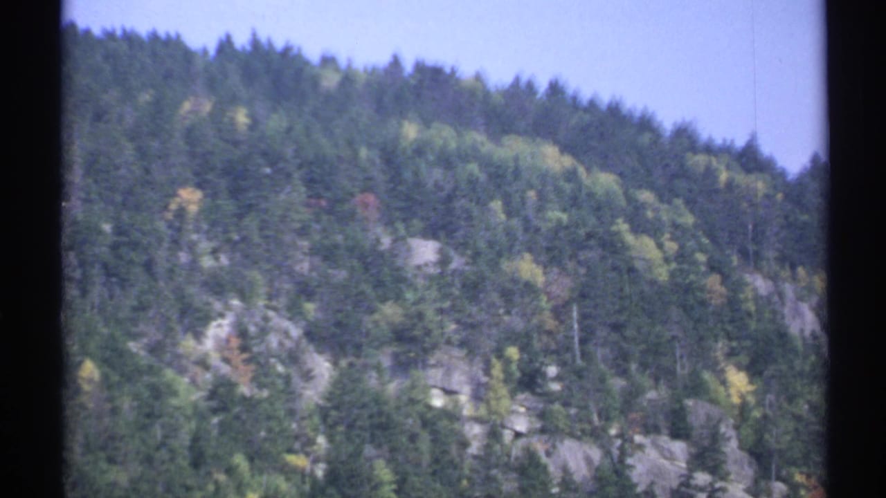 1971 New York 8mm view of a rugged wooded mountainside with exposed rock and early autumn color.