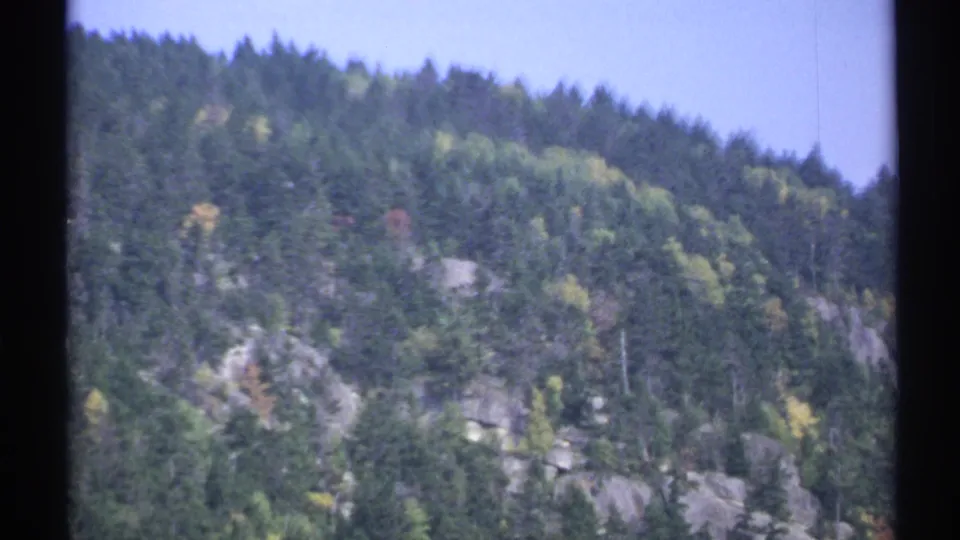 1971 New York 8mm view of a rugged wooded mountainside with exposed rock and early autumn color.