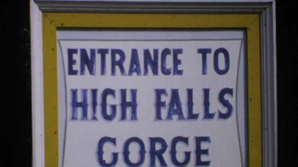 1971 New York 8mm frame with the High Falls Gorge entrance sign filling the shot, framed by yellow and gray trim.