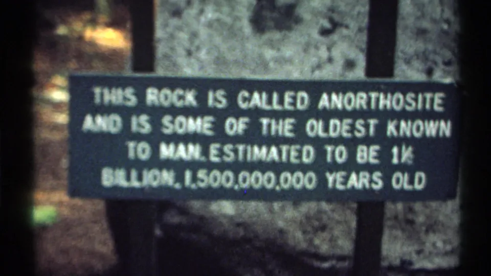 1971 New York 8mm frame showing an anorthosite information sign in front of a large rock at High Falls Gorge.