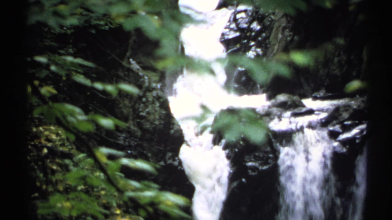 1971 New York 8mm frame showing white water cascading through a wooded rocky gorge.