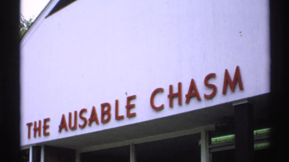 1971 New York 8mm frame showing part of a pale exterior sign with red raised letters reading THE AUSABLE CHASM.
