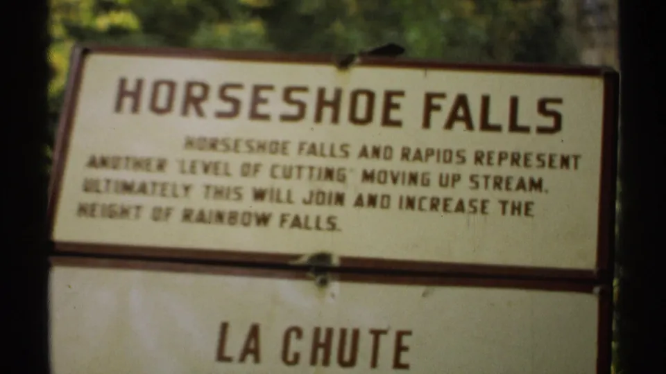 1971 New York 8mm frame showing the Horseshoe Falls information board, with most text visible and the lower La Chute panel partly in frame.