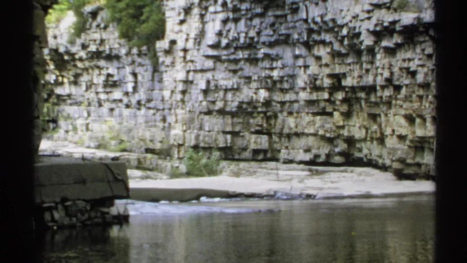 1971 New York 8mm frame of a river canyon, with a partly visible person in a light shirt near the camera and layered rock beyond.