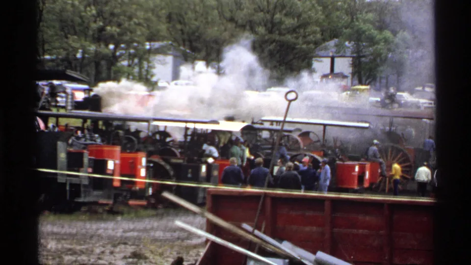 Rollag, Minnesota 1971 frame with heavy steam over the railway scene and spectators standing near red equipment.