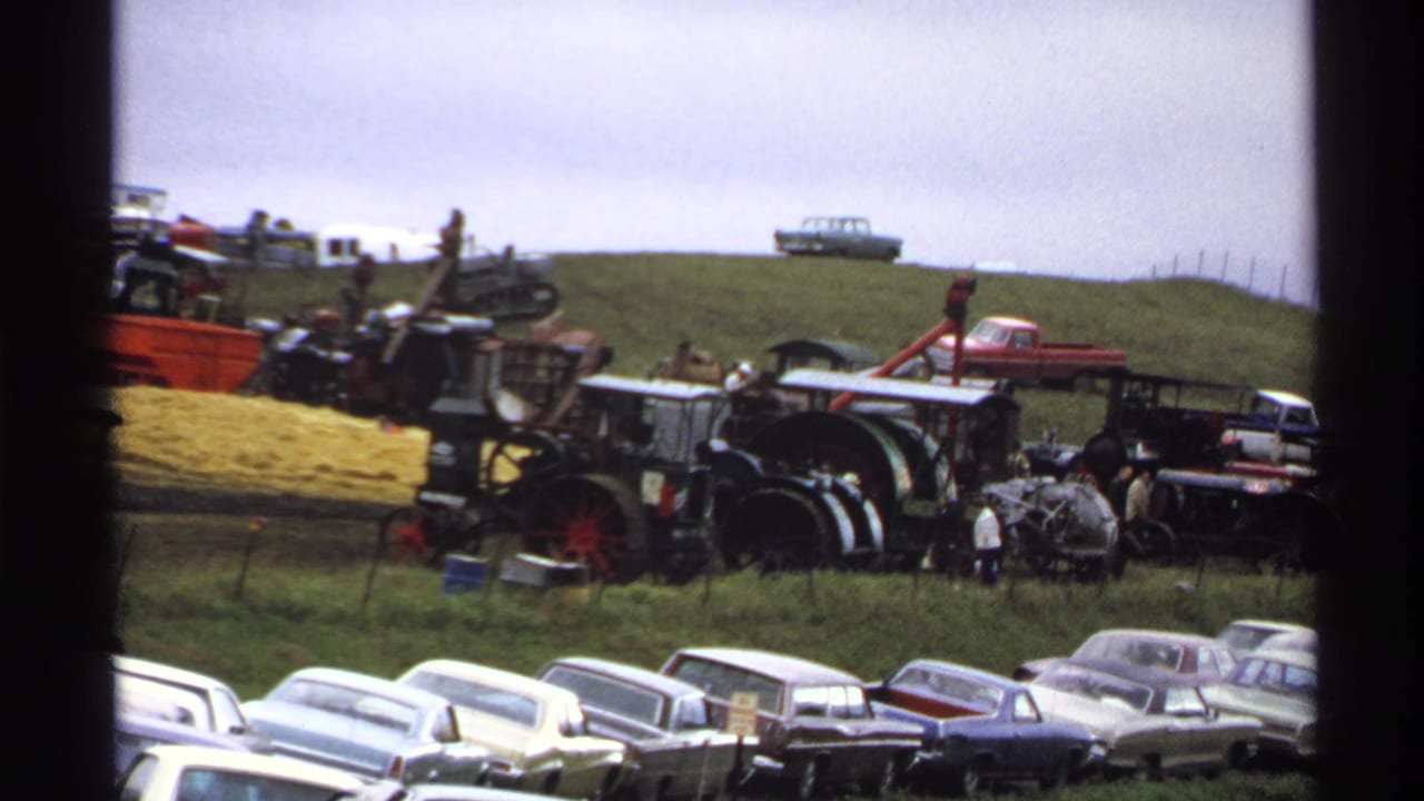 Rollag, Minnesota 1971 home-movie frame showing classic cars in front of antique tractors and farm machinery on a grassy hillside.