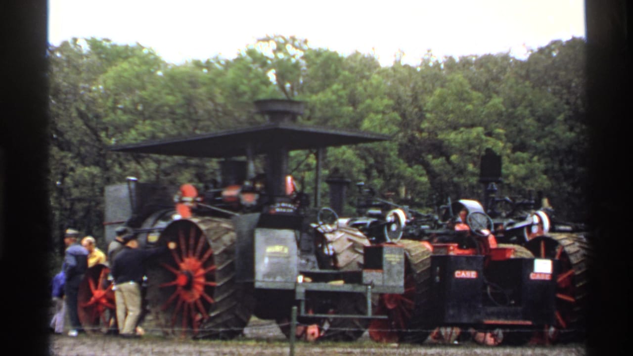 Steam tractors and fair visitors in a grassy outdoor display area.