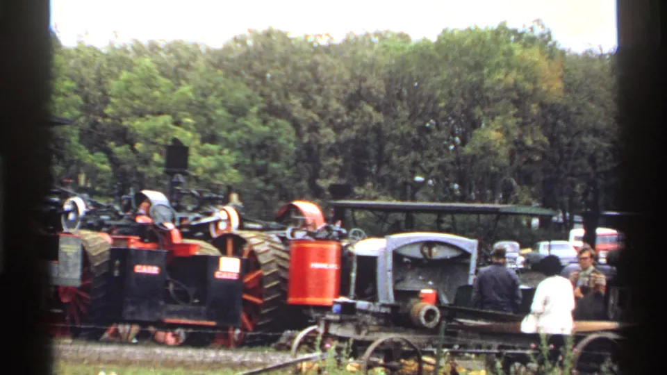 1971 Rollag, Minnesota frame showing steam machinery, a wagon or equipment cart, and fairgoers in a tree-lined outdoor setting.