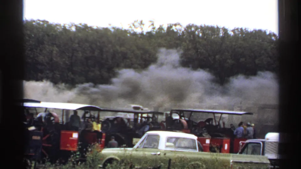 1971 Rollag, Minnesota 8mm frame showing steam traction engines, spectators, smoke, and a green and white pickup truck.
