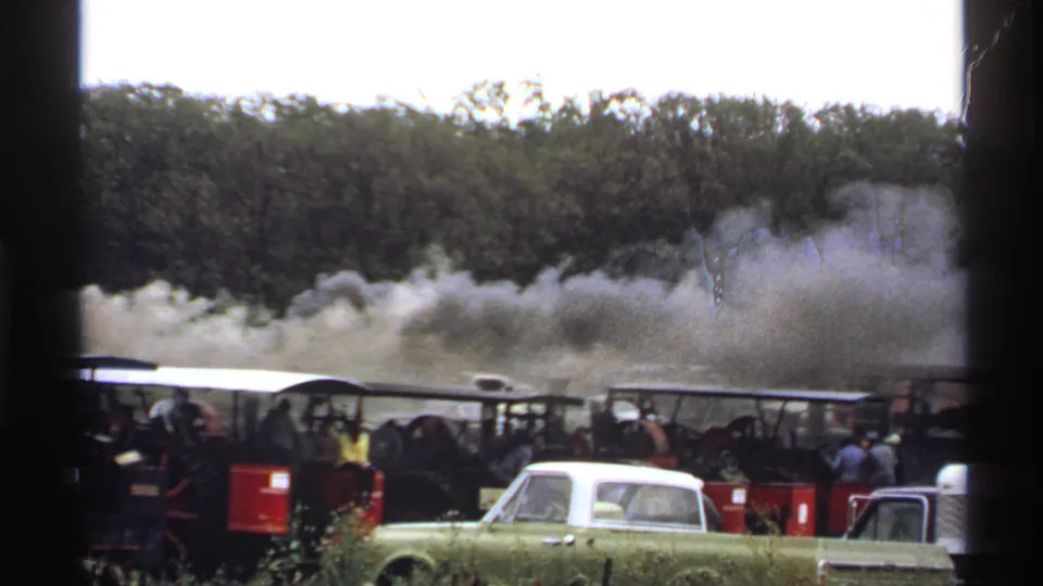 1971 Rollag, Minnesota frame with a row of steam engines, gathered spectators, thick smoke, and trees in the background.