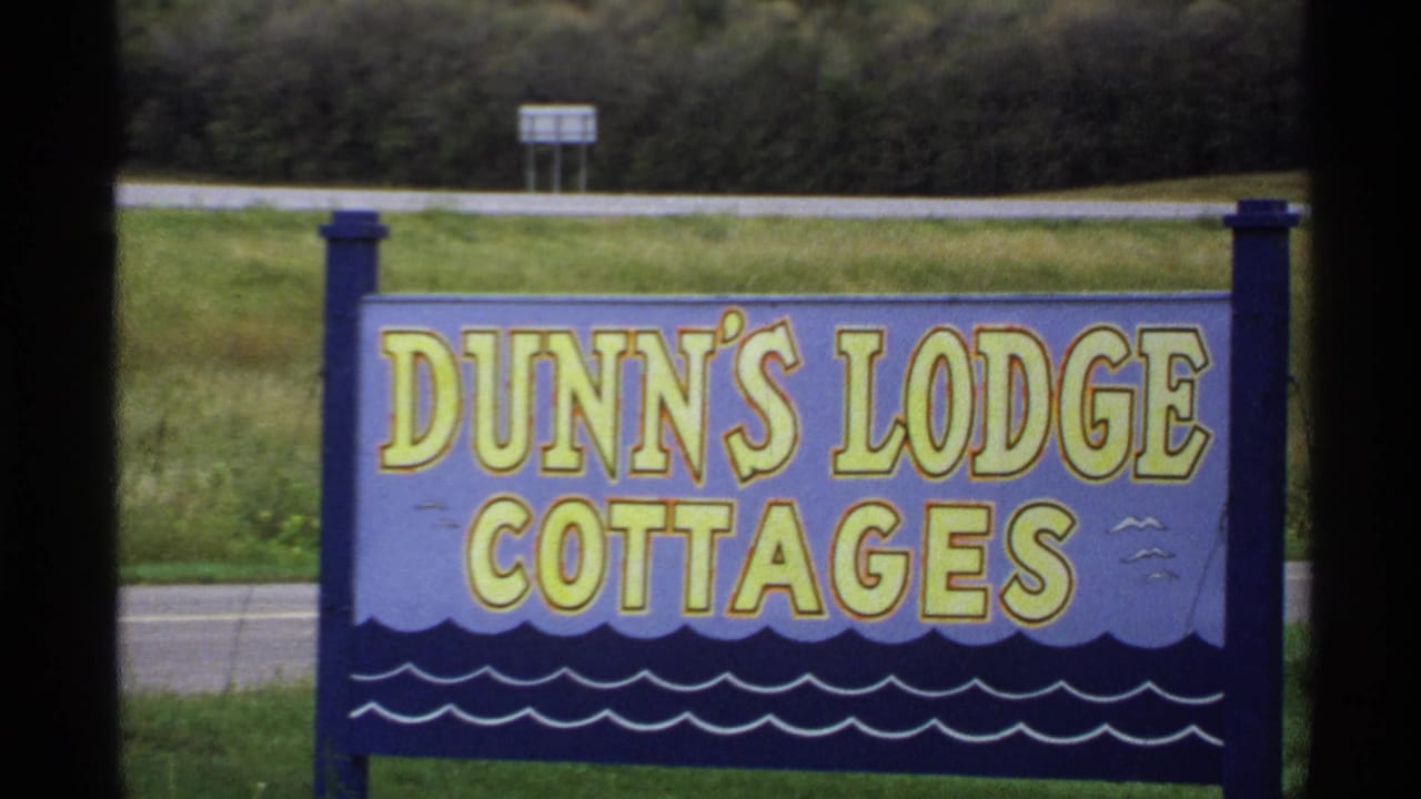 1971 Rollag, Minnesota footage showing a painted Dunn's Lodge Cottages sign near grass and a roadside edge.