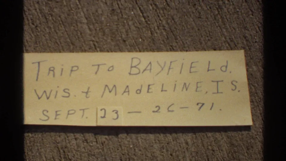 8mm frame showing a handwritten September 1971 Bayfield and Madeline Island trip note against wood grain.