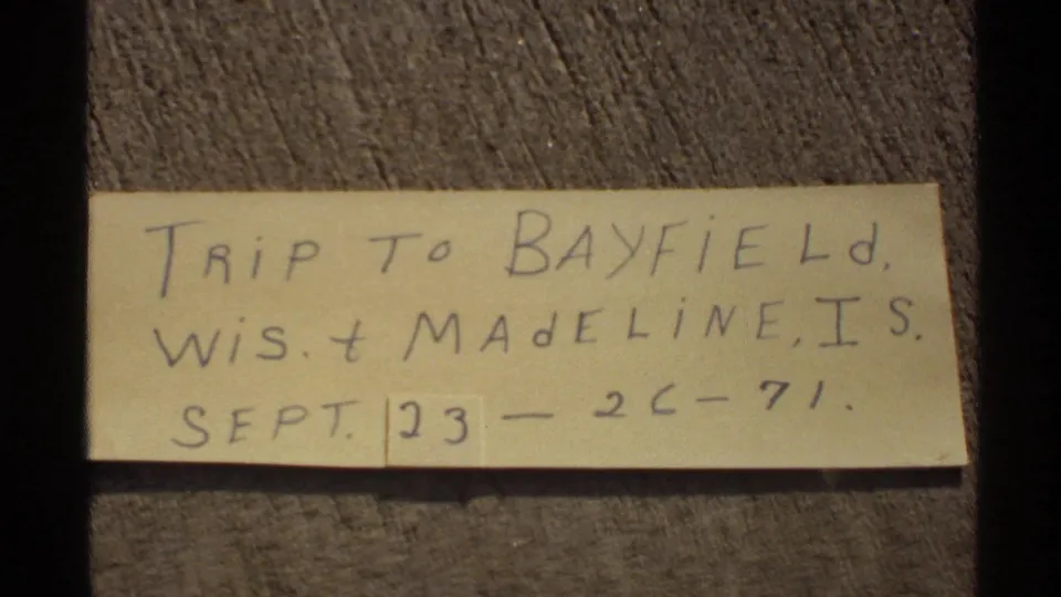 Handwritten 1971 trip note referencing Bayfield, Wisconsin and Madeline Island on a yellow slip of paper.